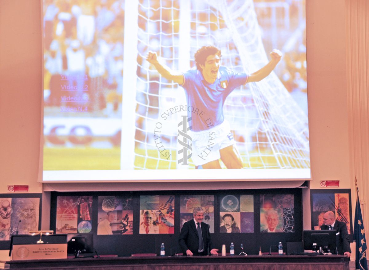Inquadratura totale di Paolo Rossi e sulla destra il presidente Walter Ricciardi, con proiezione sullo schermo del goal ai mondiali di calcio del 1982