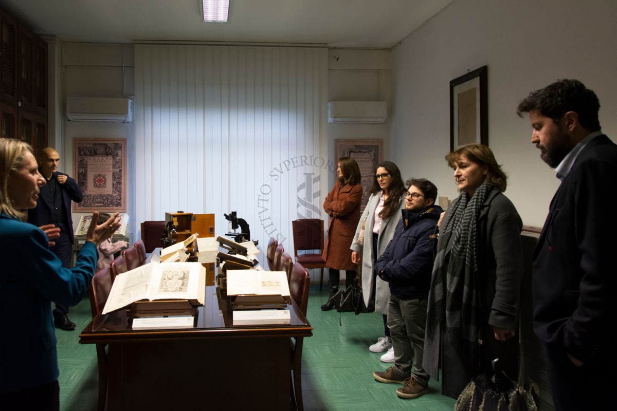 Prima della presentazione del libro "Non è mai morto nessuno" del Dott. Alessandro Mustazzolu (secondo da sinistra), la Dott.ssa Paola Ferrari, Coordinatrice del Fondo Rari della Biblioteca dell'ISS (prima da sinistra) illustra agli ospiti alcuni volumi del Fondo Antico e alcuni strumenti scientifici