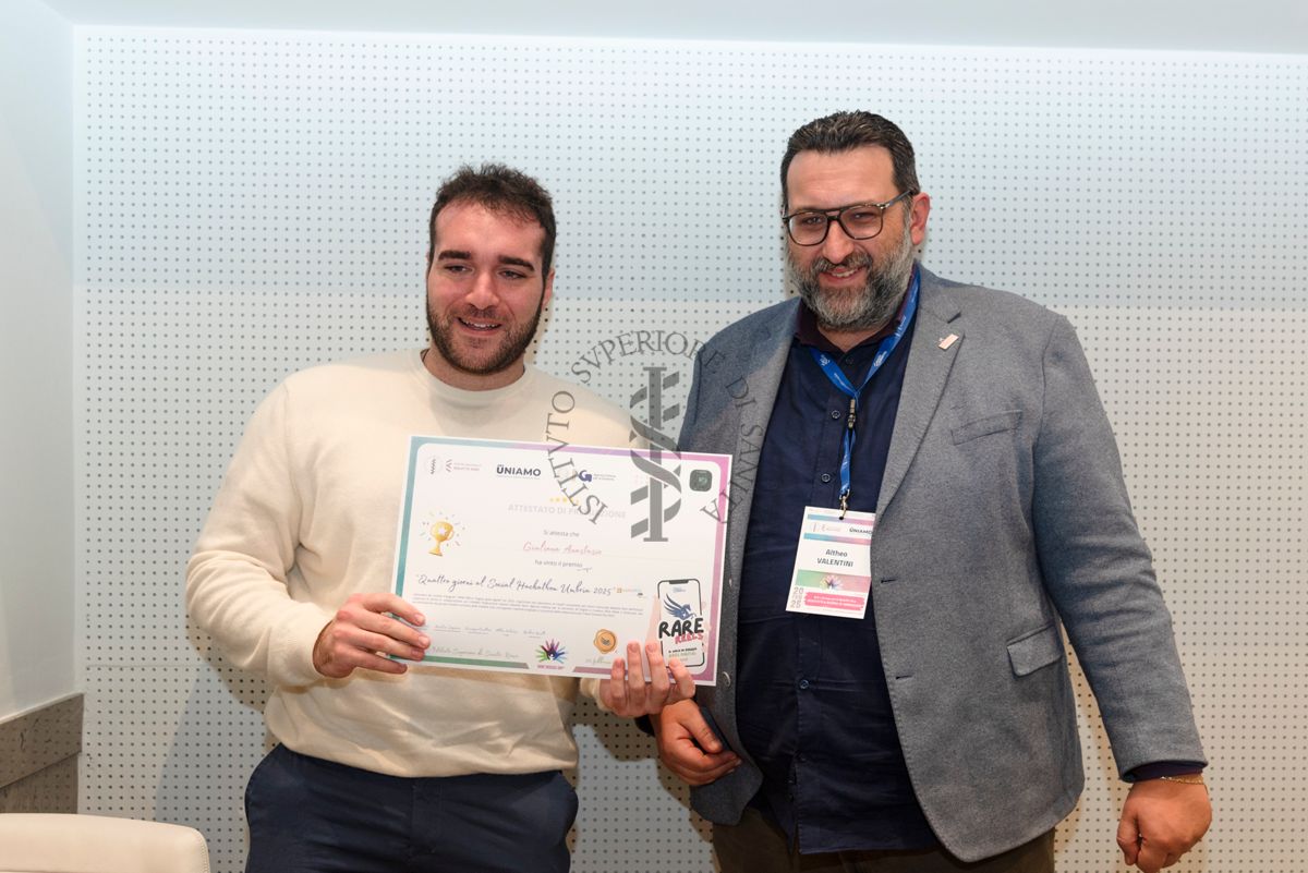 Un ragazzo mostra mostra l'attestato di partecipazione ai "Quattro giorni al social Hackathon Umbria 2025" di Giuliana Anastasio di 14 anni, vincitrice del premio grazie ad un reel che ha spiega cosa sia una malattia rara e come tramite la condivisione sui social si possa fare molto per sensibilizzare. Con lui il giornalista Altheo Valentini, Project Manager nel campo dei finanziamenti europei e nell'innovazione digitale e sociale e fondatore della European Grants International Academy Srl