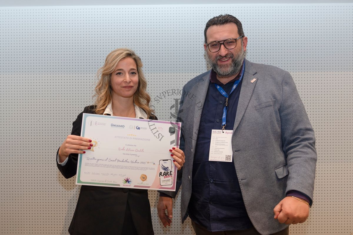 Premiazione della Dott.ssa Rada Letizia Gentile, specializzanda in anestesia e rianimazione che mostra l'attestato di partecipazione ai "Quattro giorni al social Hackathon Umbria 2025". Con lei, a destra, il giornalista Altheo Valentini, Project Manager nel campo dei finanziamenti europei e nell'innovazione digitale e sociale e fondatore della European Grants International Academy Srl (a destra)