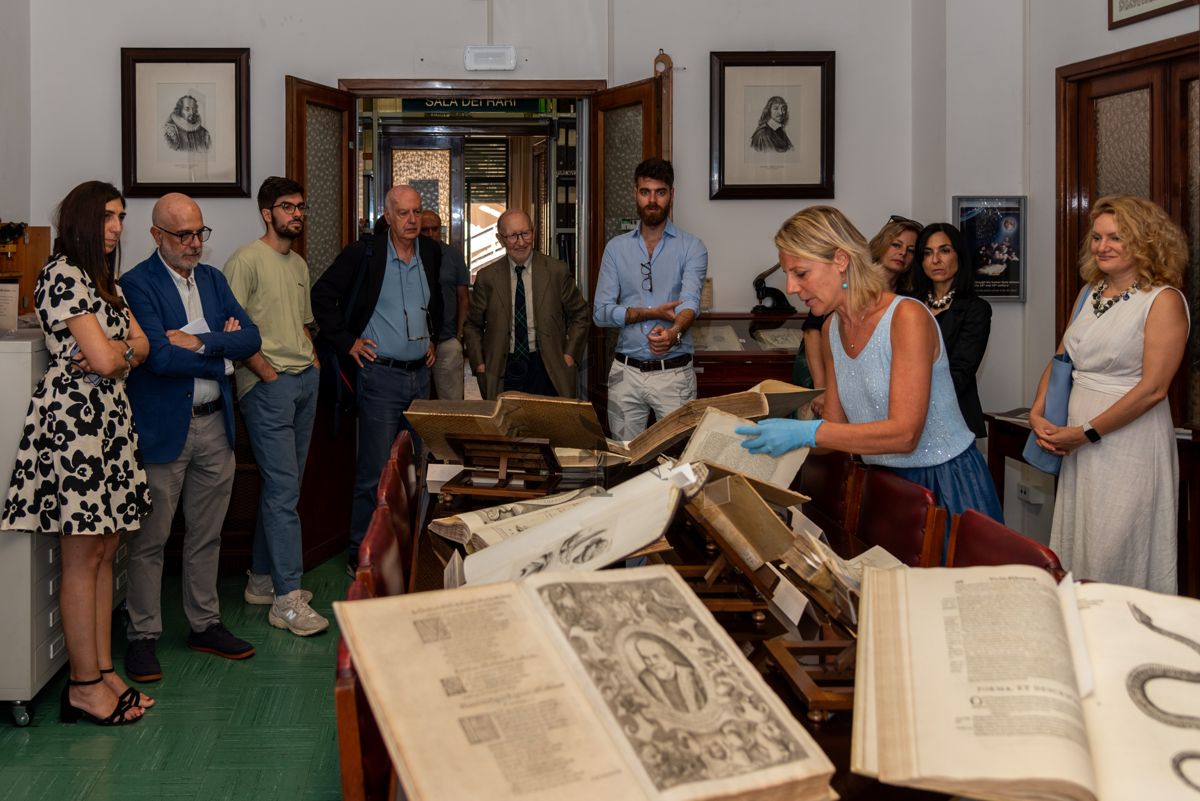 La Dott.ssa Paola Ferrari, Coordinatrice del Fondo Rari della Biblioteca dell'ISS (al centro) illustra agli ospiti alcuni volumi del Fondo Antico. Tra gli invitati ci sono la D.ssa Mirella Taranto, Renponsabile dell'Ufficio Stampa dell'ISS (prima da sinistra), il Prof. Antonio Mistretta, Responsabile del Servizio Comunicazione Scientifica dell'ISS (secondo da sinistra), il Prof. Giovanni Rezza, ex Dirigente dell'ISS e ex Direttore generale della Prevenzione Sanitaria del Ministero della Salute (quarto da sinistra) e il Prof. Antonio Cassone, ex Dirigente di Ricerca e Direttore del Dipartimento di Malattie Infettive, Parassitarie ed Immunomediate dell'ISS (quinto da sinistra)