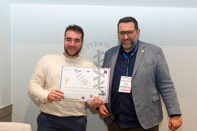 Un ragazzo mostra mostra l'attestato di partecipazione ai "Quattro giorni al social Hackathon Umbria 2025" di Giuliana Anastasio di 14 anni, vincitrice del premio grazie ad un reel che ha spiega cosa sia una malattia rara e come tramite la condivisione sui social si possa fare molto per sensibilizzare. Con lui il giornalista Altheo Valentini, Project Manager nel campo dei finanziamenti europei e nell'innovazione digitale e sociale e fondatore della European Grants International Academy Srl