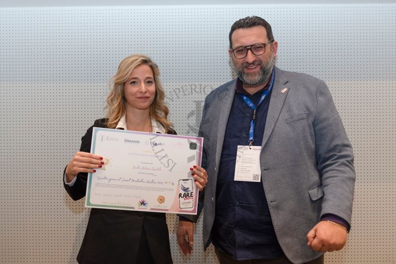 Premiazione della Dott.ssa Rada Letizia Gentile, specializzanda in anestesia e rianimazione che mostra l'attestato di partecipazione ai "Quattro giorni al social Hackathon Umbria 2025". Con lei, a destra, il giornalista Altheo Valentini, Project Manager nel campo dei finanziamenti europei e nell'innovazione digitale e sociale e fondatore della European Grants International Academy Srl (a destra)