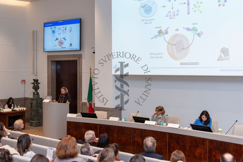 Intervento della Dott.ssa Susanna Falcucci, PhD student in Scienze delle Malattie Infettive, Microbiologia, Medicina Legale e Sanità Pubblica (a sinistra). Al tavolo dei relatori la Prof.ssa Anna Teresa Palamara, Direttore del Dipartimento di Malattie Infettive dell'Istituto Superiore di Sanità (al centro) e la Dott. Matilda Hushi del Dipartimento Malattie Infettive dell'Istituto Superiore di Sanità (a destra)