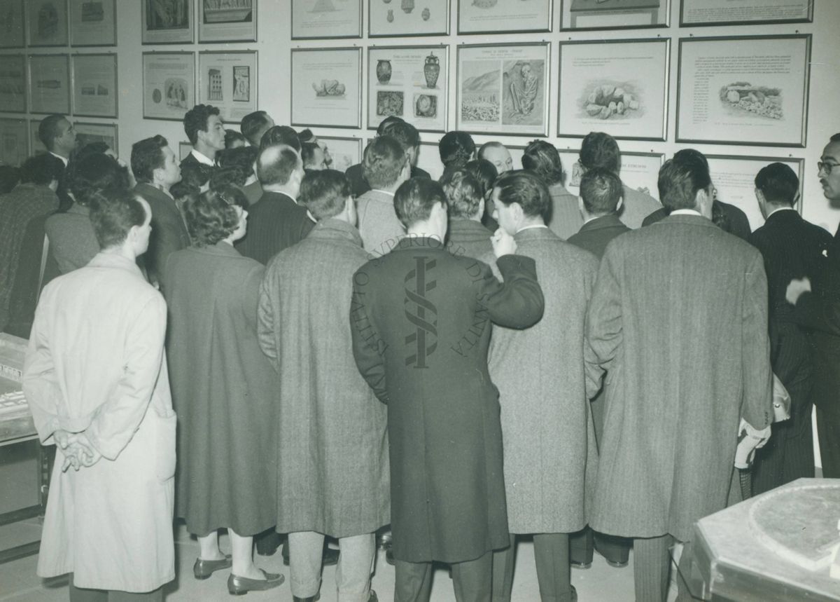 Gruppo ripreso di spalle che osserva le riproduzioni e i disegni esposti nel Museo dell'Istituto Superiore di Sanità.