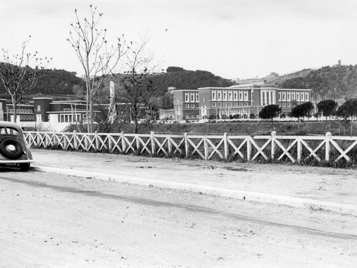 Inquadratura di una carreggiata che corre parallela al Tevere, con edifici del Foro Mussolini sullo sfondo a destra della strada