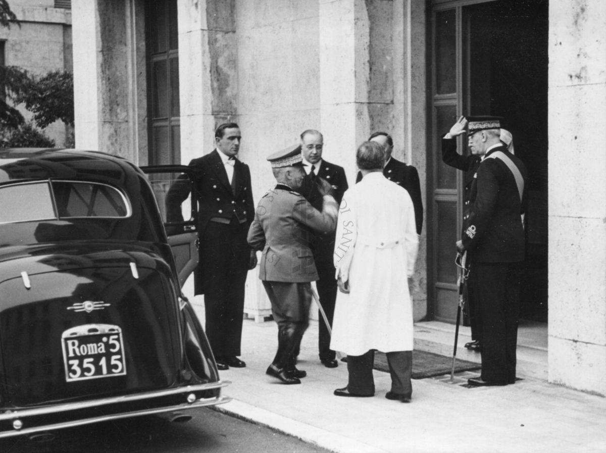 Vittorio Emanuele III, in visita all'Istituto di Sanità Pubblica, entra in Istituto e riceve i saluti di alcune persone che lo accolgono, tra cui il Prof. Domenico Marotta