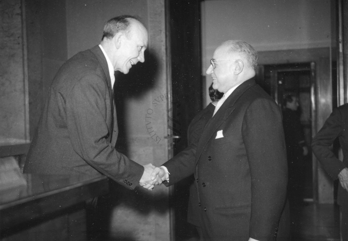 Il Prof. Holter (a sinistra), al lato del tavolo dei relatori, stringe la mano del Prof. Marotta nell'aula magna dell'Istituto Superiore di Sanità in occasione della conferenza tenuta dal Prof. Holter