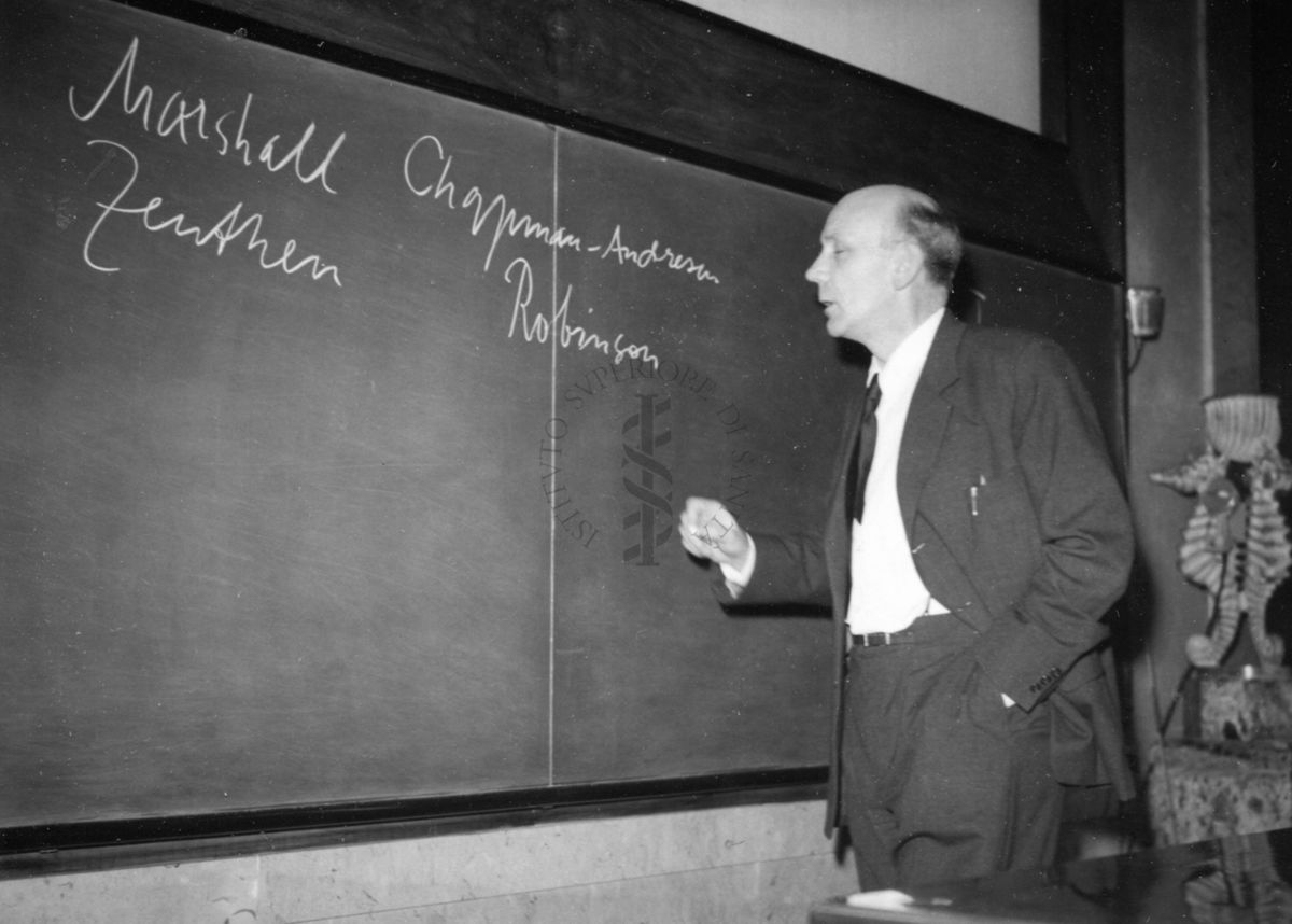 Il Prof. Holter rivolto verso la lavagna di ardesia, dietro il tavolo dei relatori, in occasione della conferenza tenuta all'aula magna dell'Istituto Superiore di Sanità