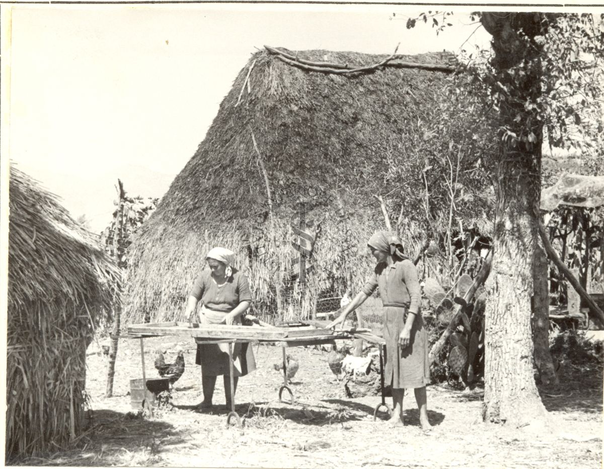 Villaggio di capanne con donne al lavoro.