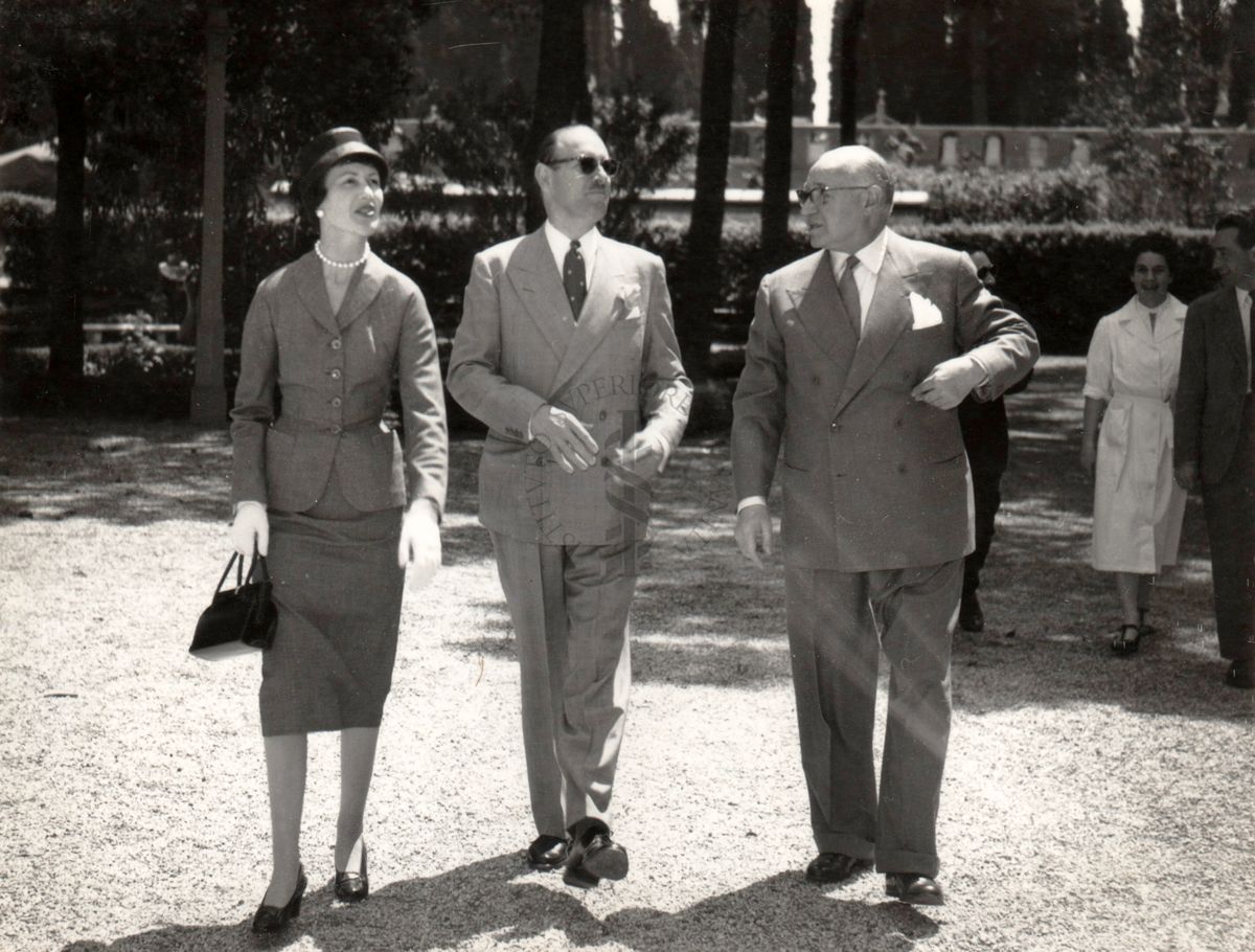 L'Ambasciatore Britannico Sir Ashley Clarke (al centro) e signora (lato sinistro della foto), conversano nel giardino dell'Istituto Superiore di Sanità con il prof. Domenico Marotta (lato destro). Sullo sfondo sono riconoscibili i cipressi e le mura del cimitero del Verano.