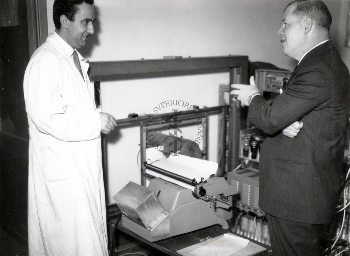 Il prof. Makeen (lato destro) conversa con il prof. Francesco Pocchiari (lato sinistro) davanti ad uno strumento di laboratorio.