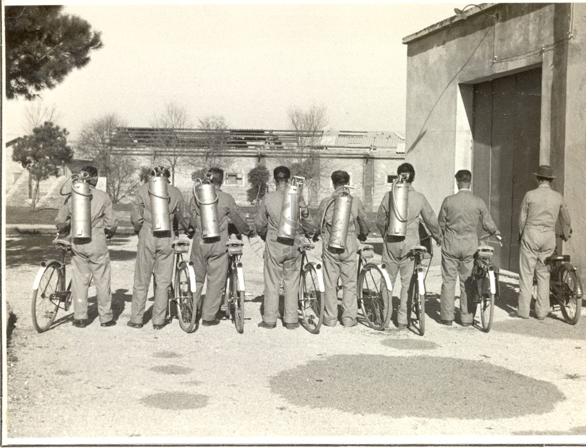 Squadra attrezzata di biciclette per la disinfestazione con D.D.T., fotografata di spalle