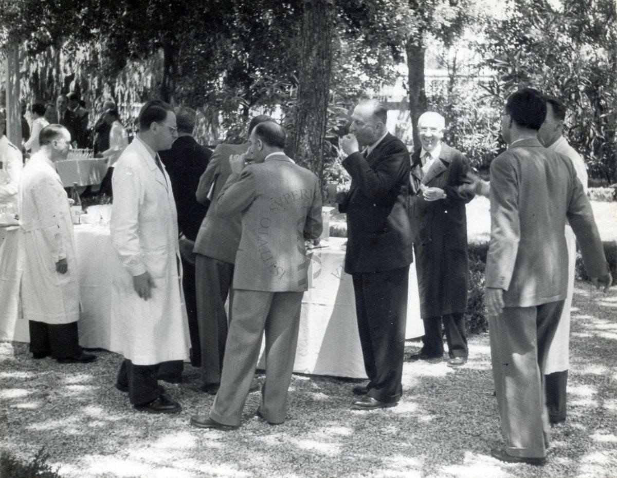 Un gruppo di congressisti ripresi intorno ad un buffet allestito nel giardino dell'Istituto Superiore di Sanità