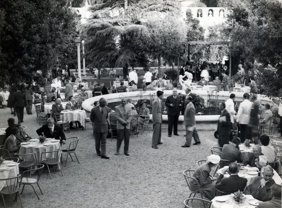 Foto del giardino dell'Istituto Superiore di Sanità con i tavoli allestiti in occasione del banchetto tenuto per il IX Congresso internazionale dell'industria agraria. Sullo sfondo la fontana nel giardino.