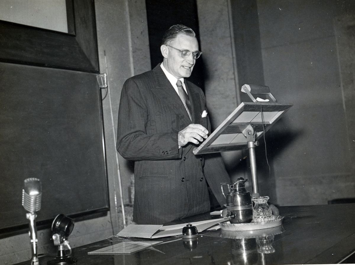 Il Prof. H. Corwin Hinshaw ripreso in piedi a leggere da un leggìo in occasione della conferenza tenuta all'Istituto Superiore di Sanità