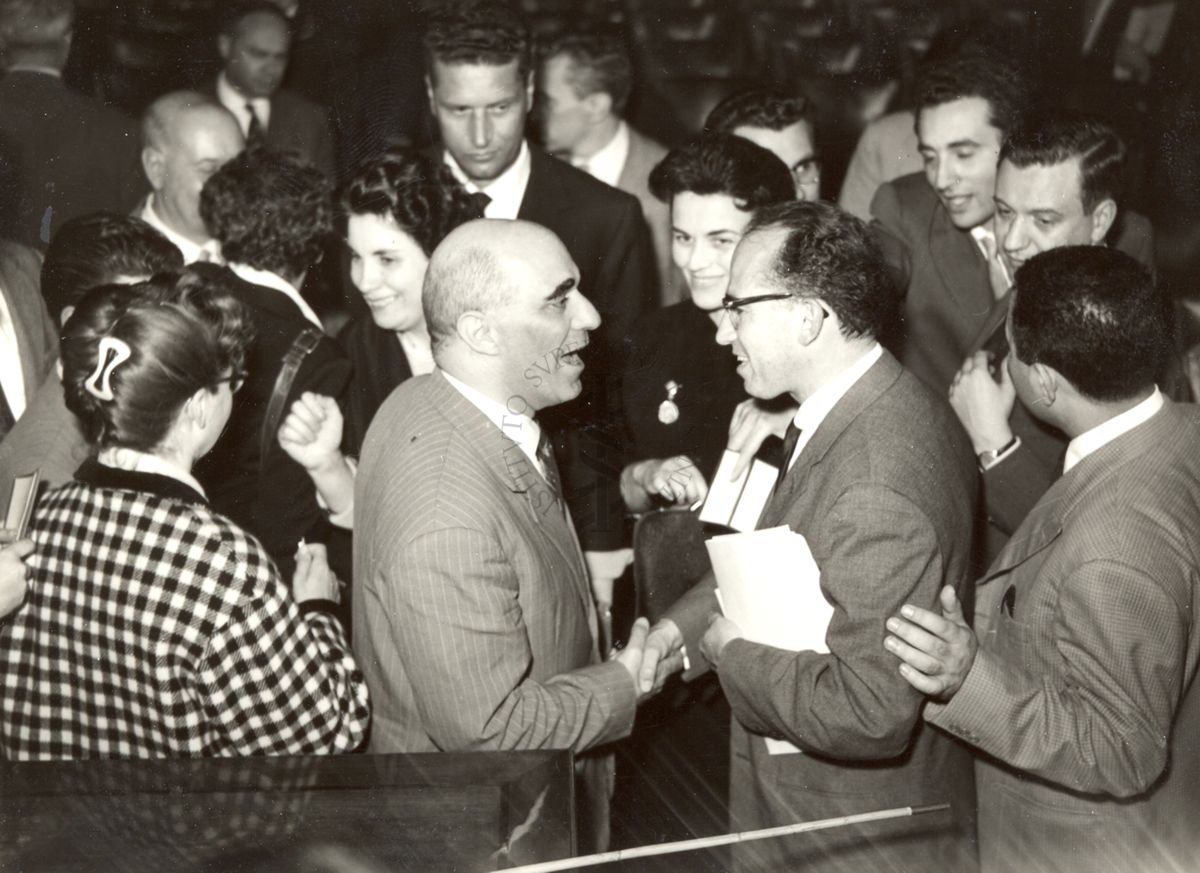 Il Prof. Salk di profilo (a destra) circondato di persone in occasione della conferenza tenuta all'Istituto Superiore di Sanità