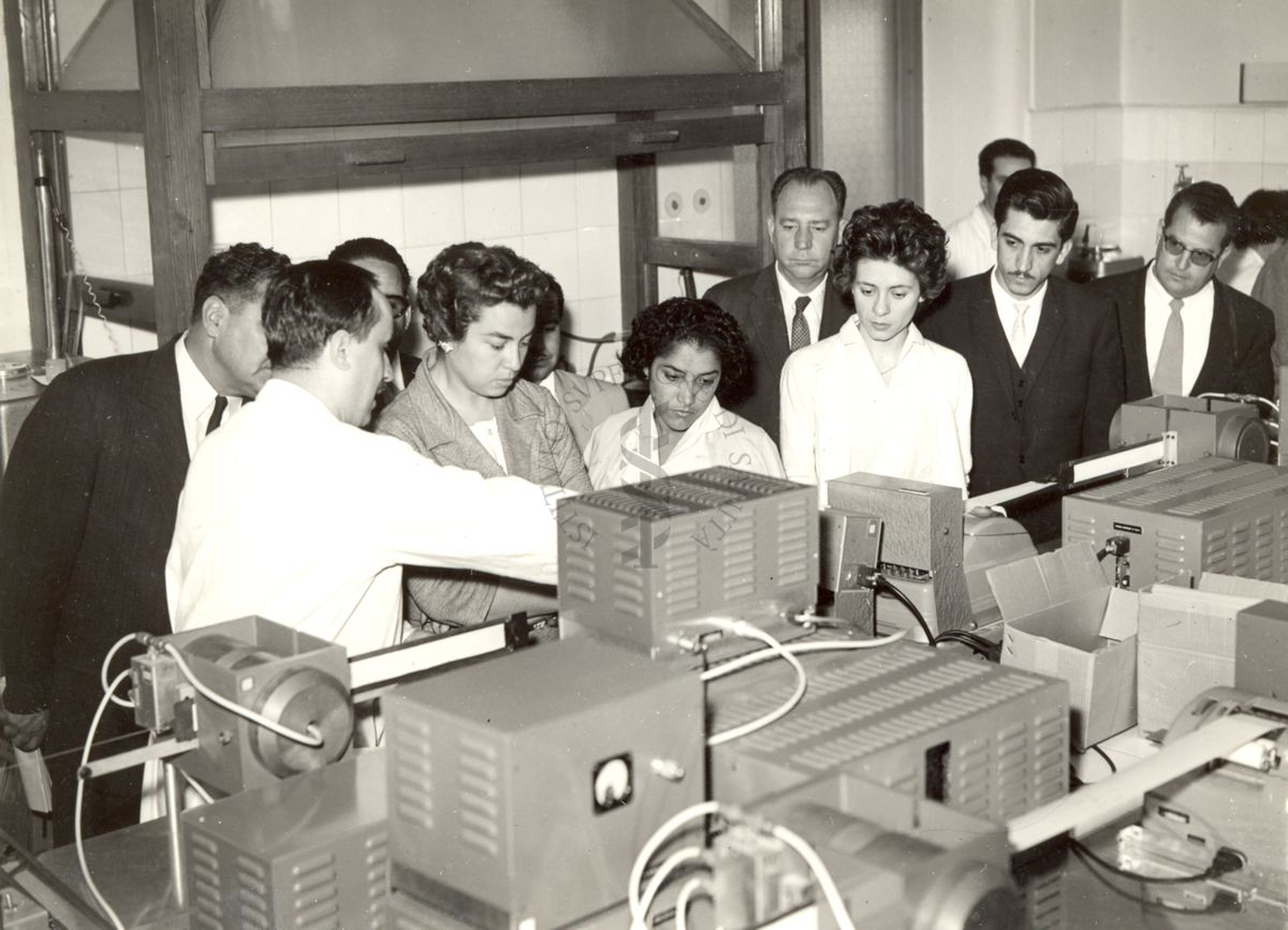 Il gruppo in visita all'Istituto Superiore di Sanità presso i laboratori, intorno a macchinari illustrati da un ricercatore dell'Istituto in camice bianco