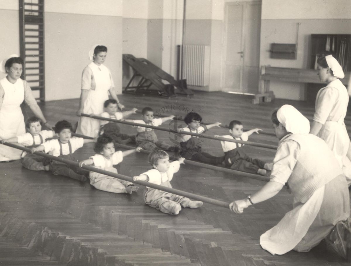 Sala per la ginnastica collettiva dell'Istituto Ortopedico "Luigi Spolverini" di Ariccia (Roma) - delle infermiere sorreggono alcune aste per guidare i movimenti dei bambini