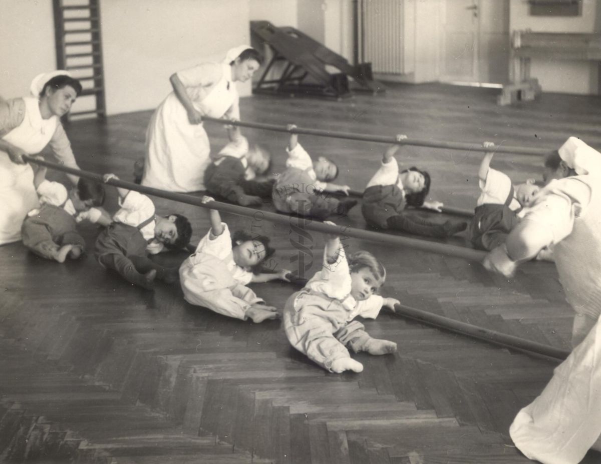 Sala per la ginnastica collettiva dell'Istituto Ortopedico "Luigi Spolverini" di Ariccia (Roma) - delle infermiere sorreggono alcune aste per guidare i movimenti dei bambini