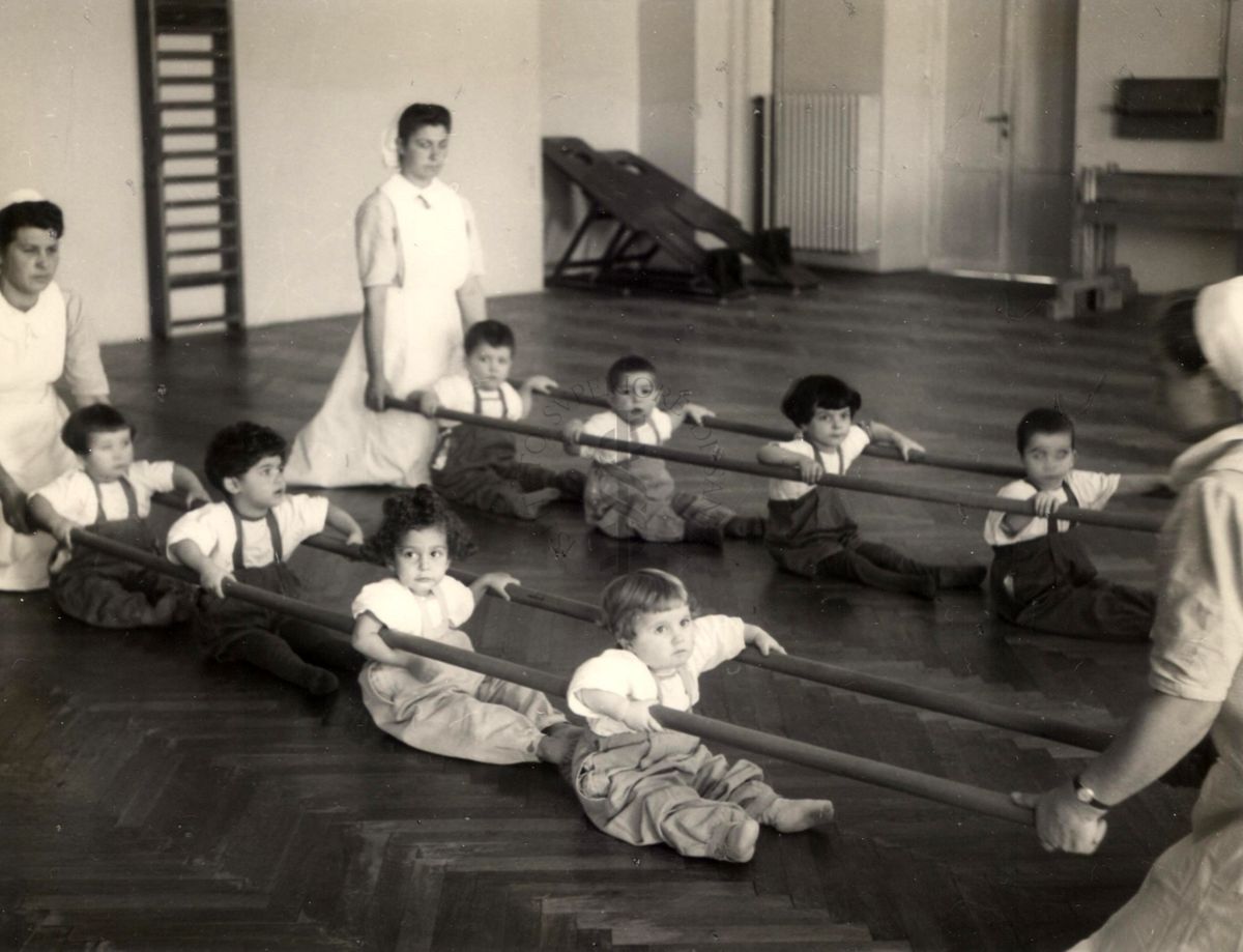 Sala per la ginnastica collettiva dell'Istituto Ortopedico "Luigi Spolverini" di Ariccia (Roma) - delle infermiere sorreggono alcune aste per guidare i movimenti dei bambini