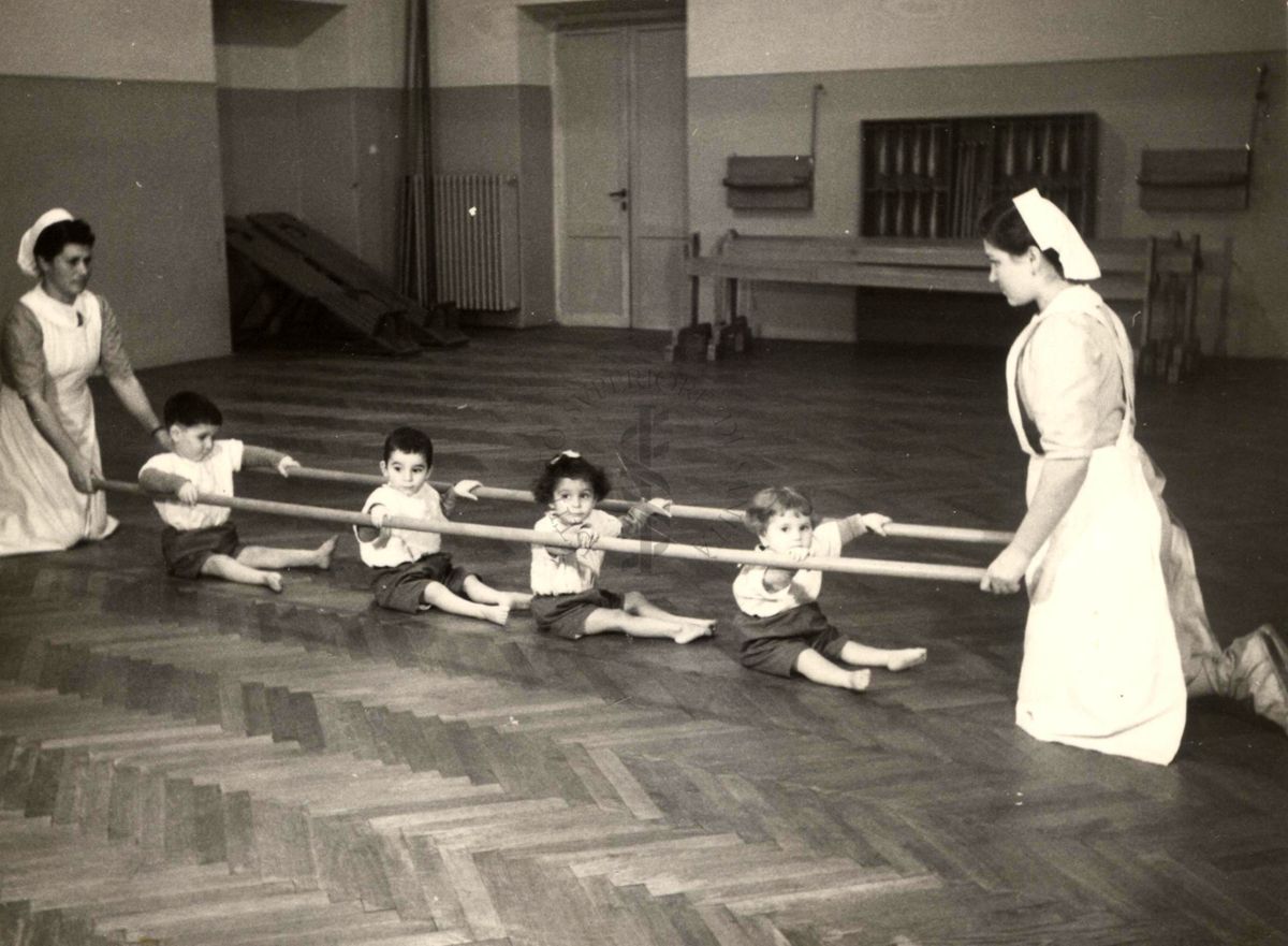 Sala per la ginnastica collettiva dell'Istituto Ortopedico "Luigi Spolverini" di Ariccia (Roma) - delle infermiere sorreggono alcune aste per guidare i movimenti dei bambini