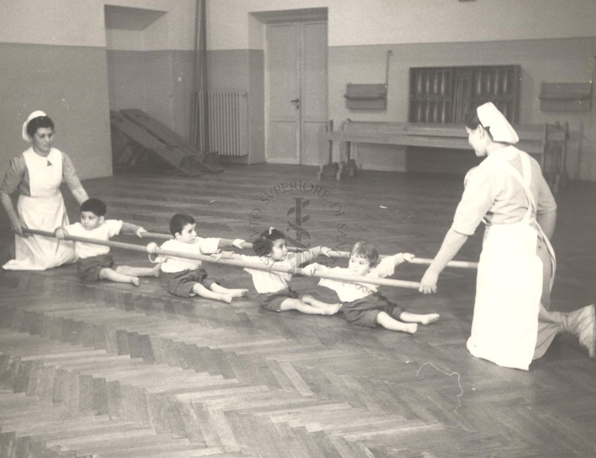 Sala per la ginnastica collettiva dell'Istituto Ortopedico "Luigi Spolverini" di Ariccia (Roma) - delle infermiere sorreggono alcune aste per guidare i movimenti dei bambini