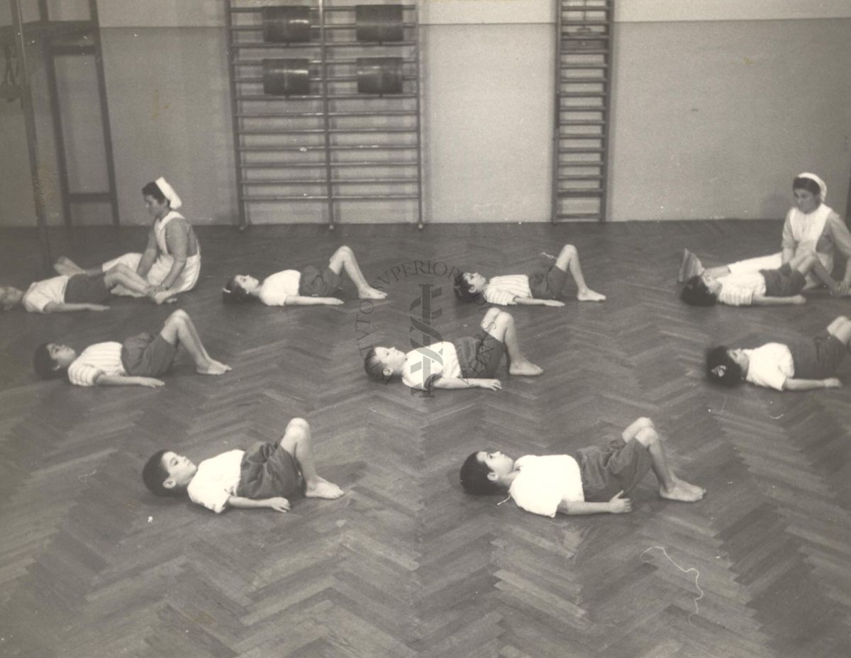 Sala per la ginnastica collettiva dell'Istituto Ortopedico "Luigi Spolverini" di Ariccia (Roma) - delle infermiere controllano la postura di un gruppo di bambini che svolgono esercizi ginnici