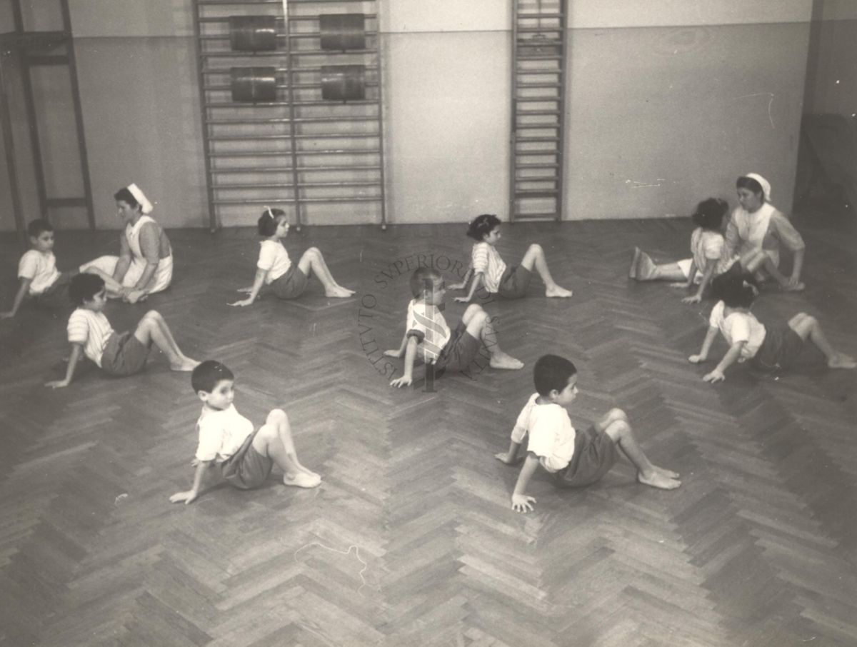 Sala per la ginnastica collettiva dell'Istituto Ortopedico "Luigi Spolverini" di Ariccia (Roma) - delle infermiere controllano la postura di un gruppo di bambini che svolgono esercizi ginnici