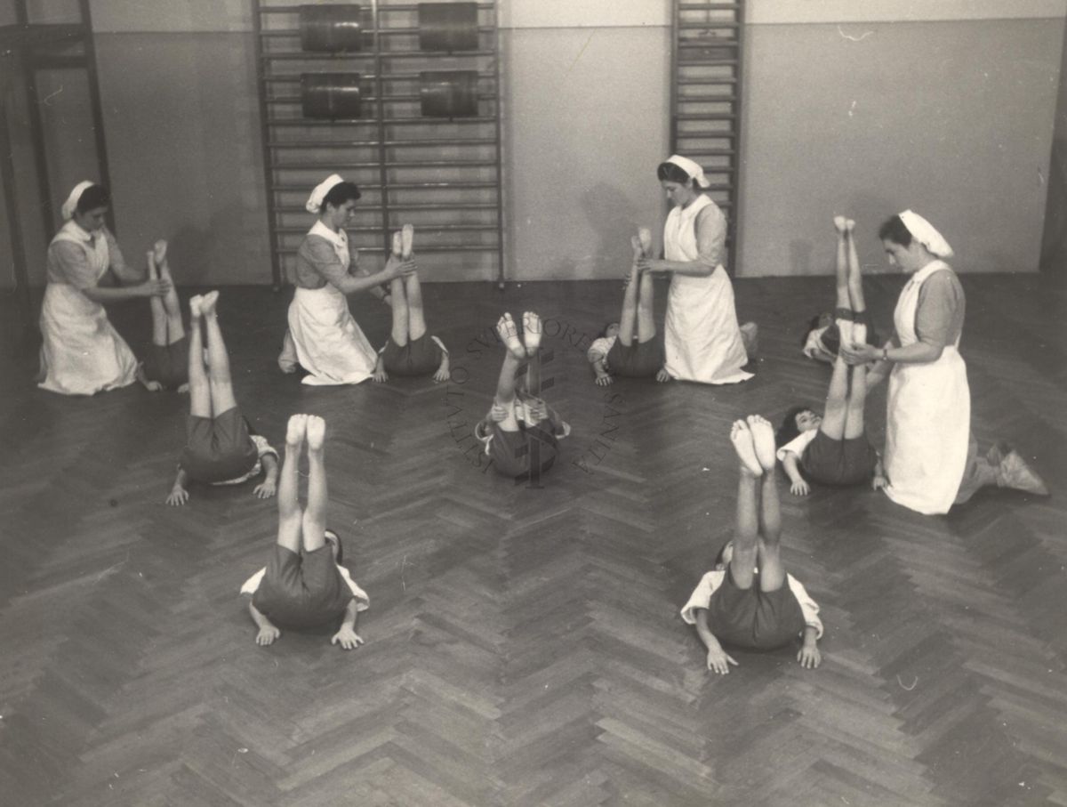 Sala per la ginnastica collettiva dell'Istituto Ortopedico "Luigi Spolverini" di Ariccia (Roma) - delle infermiere controllano la postura di un gruppo di bambini che svolgono esercizi ginnici