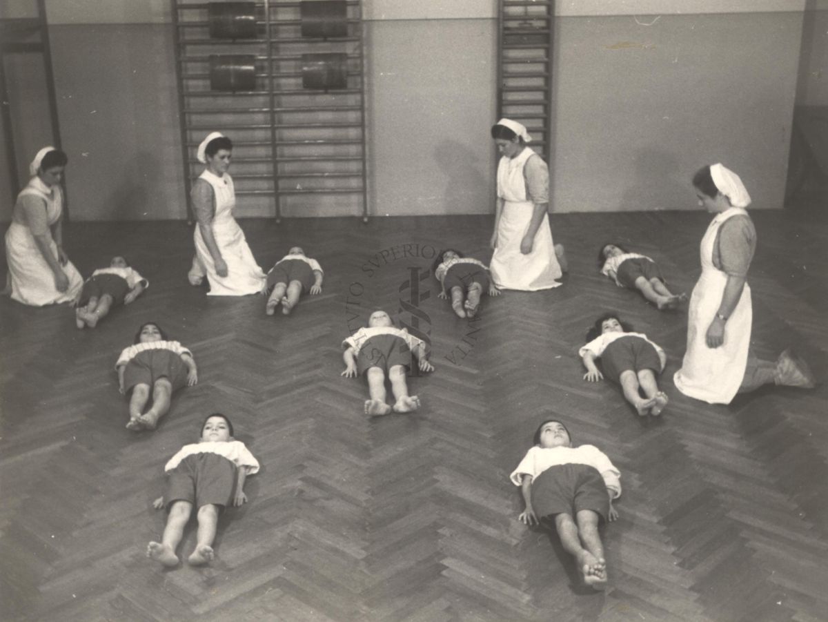 Sala per la ginnastica collettiva dell'Istituto Ortopedico "Luigi Spolverini" di Ariccia (Roma) - delle infermiere controllano la postura di un gruppo di bambini che svolgono esercizi ginnici