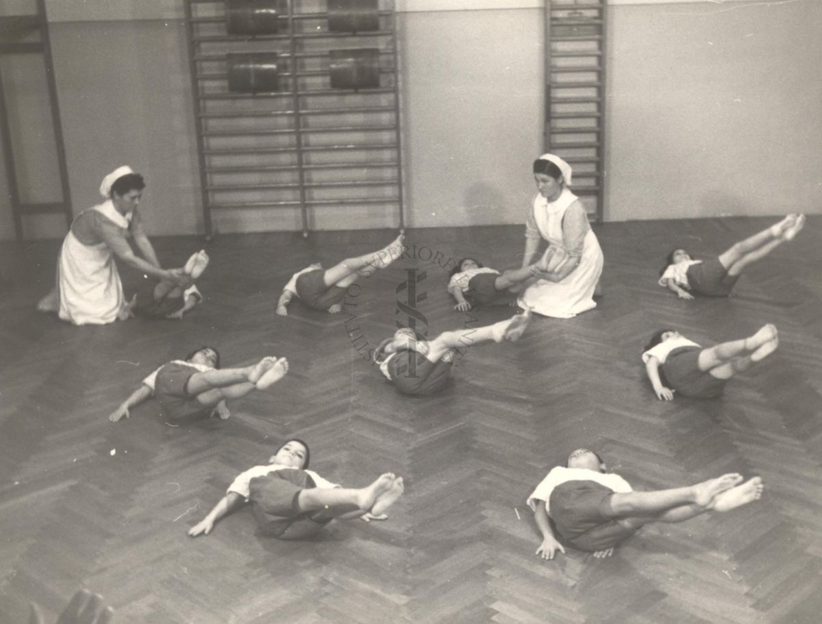 Sala per la ginnastica collettiva dell'Istituto Ortopedico "Luigi Spolverini" di Ariccia (Roma) - delle infermiere controllano la postura di un gruppo di bambini che svolgono esercizi ginnici