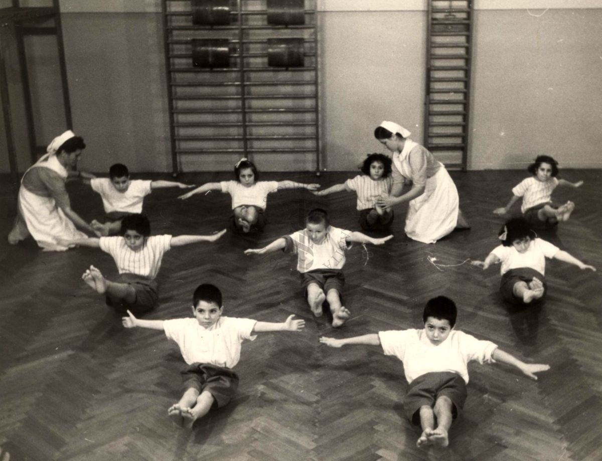 Sala per la ginnastica collettiva dell'Istituto Ortopedico "Luigi Spolverini" di Ariccia (Roma) - delle infermiere controllano la postura di un gruppo di bambini che svolgono esercizi ginnici