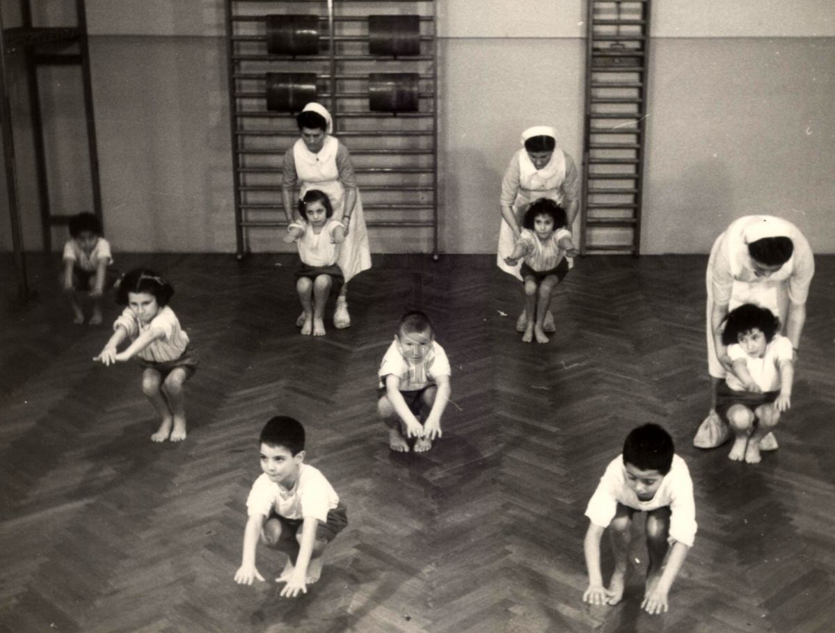 Sala per la ginnastica collettiva dell'Istituto Ortopedico "Luigi Spolverini" di Ariccia (Roma) - delle infermiere controllano la postura di un gruppo di bambini che svolgono esercizi ginnici