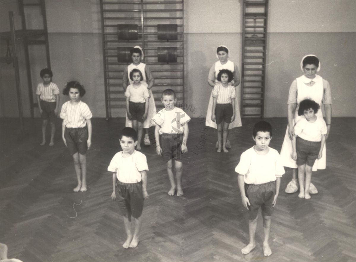 Sala per la ginnastica collettiva dell'Istituto Ortopedico "Luigi Spolverini" di Ariccia (Roma) - delle infermiere controllano la postura di un gruppo di bambini che svolgono esercizi ginnici