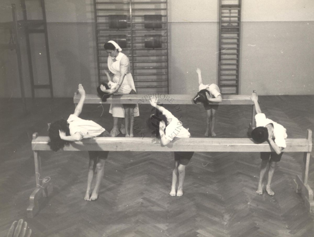 Sala per la ginnastica collettiva dell'Istituto Ortopedico "Luigi Spolverini" di Ariccia (Roma) - un'infermiera controlla la postura di un gruppo di bambini che svolgono esercizi ginnici con l'ausilio di due assi