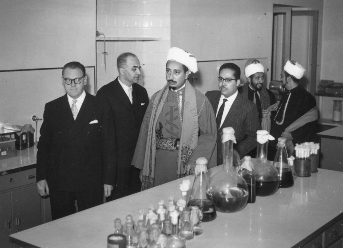 Il principe dello Yemen e il suo seguito visitano un laboratorio dell'Istituto Superiore di Sanità in cui è allestito un bancone con vetreria per esperimenti