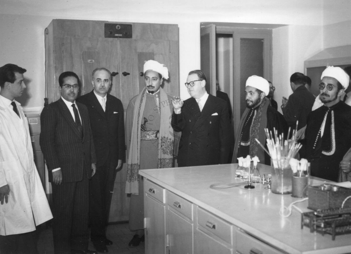 Il principe dello Yemen e il suo seguito visitano un laboratorio dell'Istituto Superiore di Sanità in cui è allestito un bancone con vetreria per esperimenti