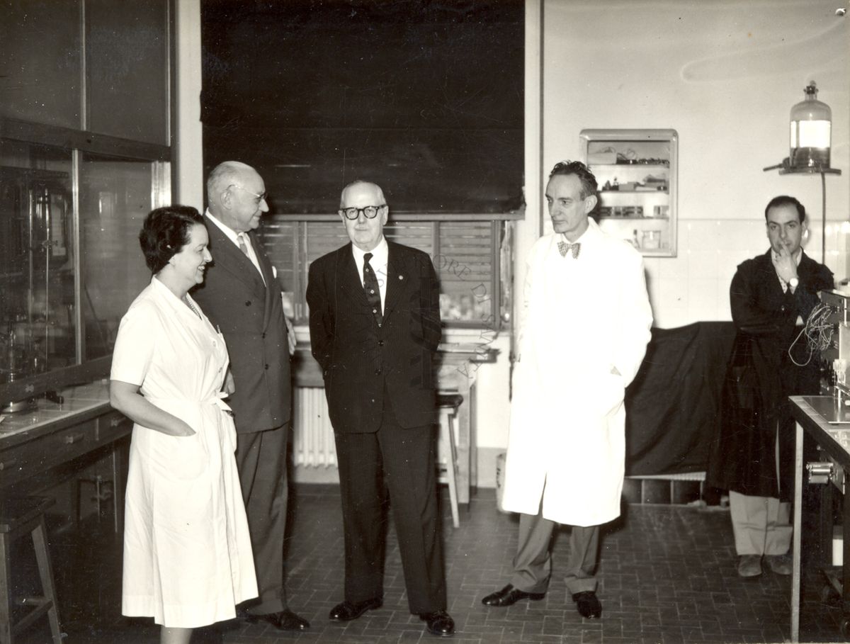 Il Prof. Bernard Houssay (vestito scuro, al centro) visita l'Istituto Superiore di Sanità, accompagnato a sinistra del Prof. Domenico Marotta e dalla Dr.ssa Filomena Nitti; mentre, a destra c'è il Prof. Daniel Bovet (camice bianco) ed un assistente di laboratorio (camice scuro)