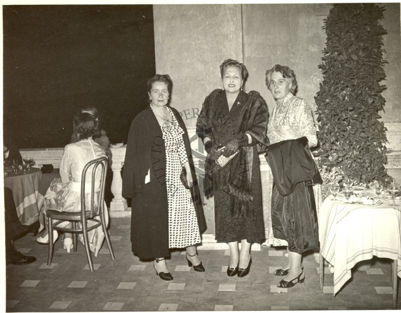 Tre donne in posa riprese all'aperto durante il ricevimento in Campidoglio offerto dal Sindaco di Roma in occasione del Congresso accanto ad un tavolino.