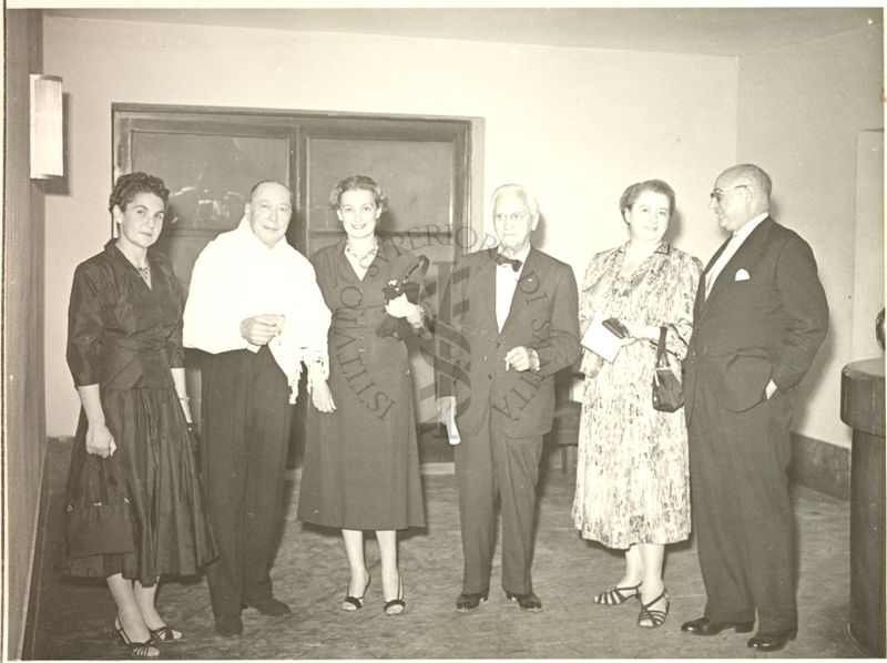 Foto di gruppo in occasione del Concerto tenuto nell'Aula Magna della Città Universitaria. Ripresi: il Maestro d'orchestra (secondo da sinistra), Prof. Marotta (ultimo a destra) insieme ad un uomo e a tre donne.