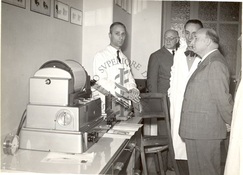 Il Prof. Bovet spiega uno strumento da laboratorio all'On. Scelba. In fondo si vede il Prof. Marotta