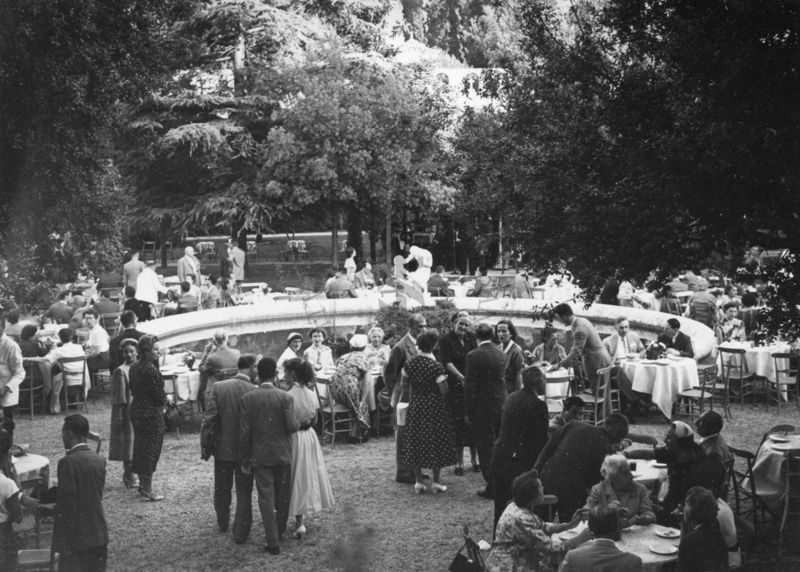 Ripresa dall'alto del giardino dell'Istituto Superiore di Sanità e della fontana intorno alla quale sono disposti i tavoli del ricevimento e i partecipanti al Congresso, disposti sia seduti sia in piedi