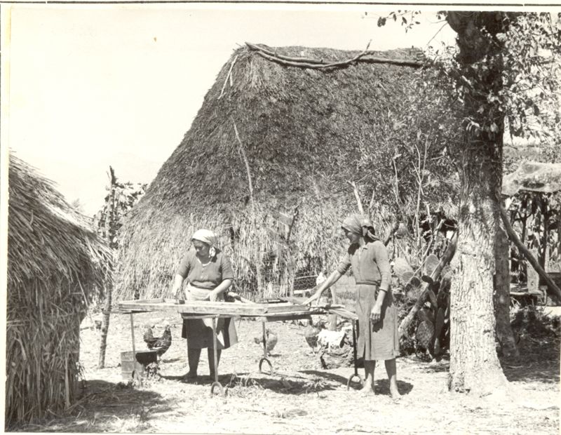 Villaggio di capanne con donne al lavoro.