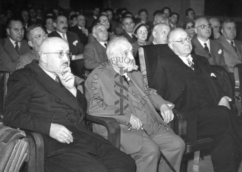 Foto di tre dei presenti in prima fila alla conferenza tenuta dal Prof. Semerano  dell'Università di Padova nell'aula magna dell'Istituto Superiore di Sanità. Tra gli inquadrati il Prof. Marotta (ultimo a destra).