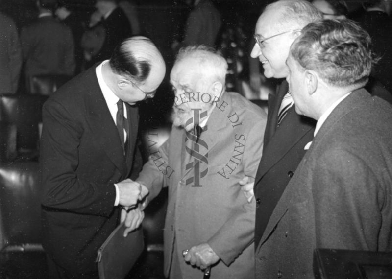 Il Prof. Semerano (a sinistra) stringe la mano ad uno dei presenti alla sua conferenza tenuta nell'aula magna dell'Istituto Superiore di Sanità. Nella foto è presente il Prof. Marotta (terzo a destra).