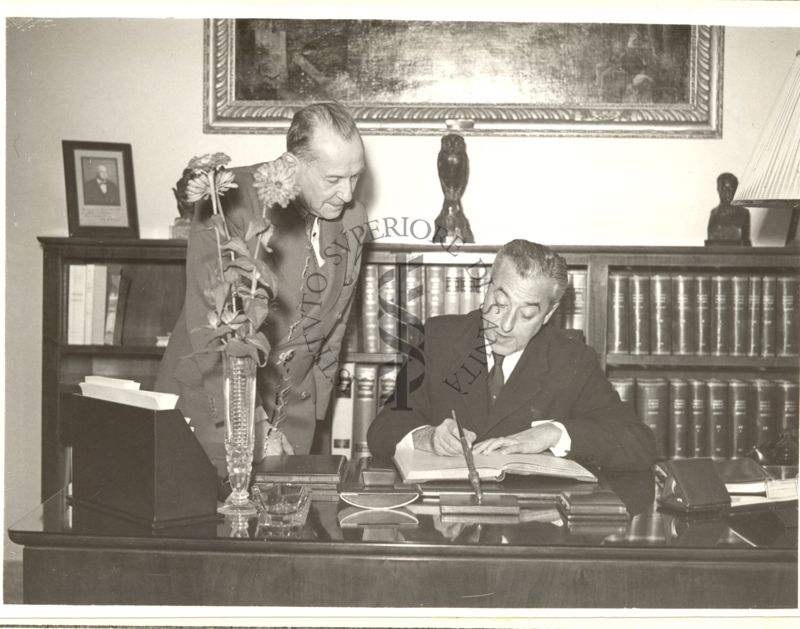 Il Prof. Arthur Mirsky, alla scrivania del Prof. Domenico Marotta, che appone la sua firma; accanto, in piedi, il Dott. Massimo Pantaleoni