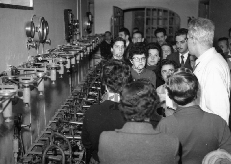 Il gruppo degli studenti uruguaiani in visita all'Istituto Superiore di Sanità all'interno di uno dei laboratori, in presenza di un dipendente dell'Istituto in camice bianco.