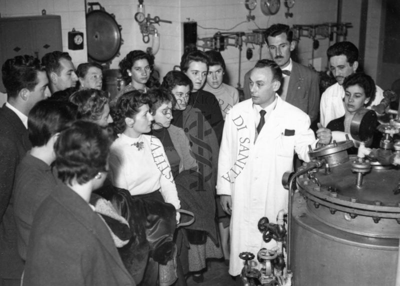 Il gruppo degli studenti uruguaiani in visita all'Istituto Superiore di Sanità all'interno di uno dei laboratori alla presenza di due dipendenti dell'Istituto in camice bianco