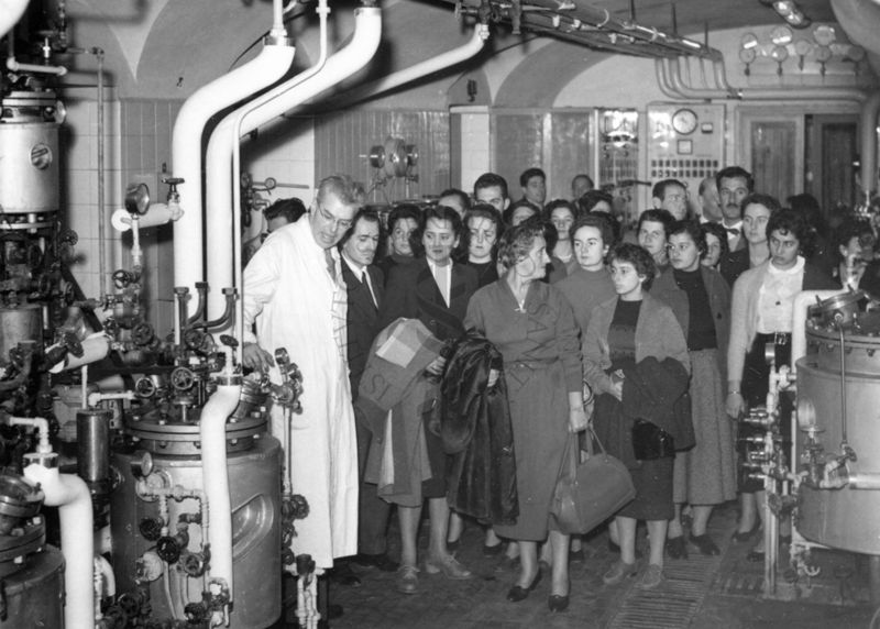 Il gruppo degli studenti uruguaiani in visita all'Istituto Superiore di Sanità all'interno di uno dei laboratori alla presenza di un dipendente dell'Istituto in camice bianco (sulla sinistra) che illustra i macchinari presenti.